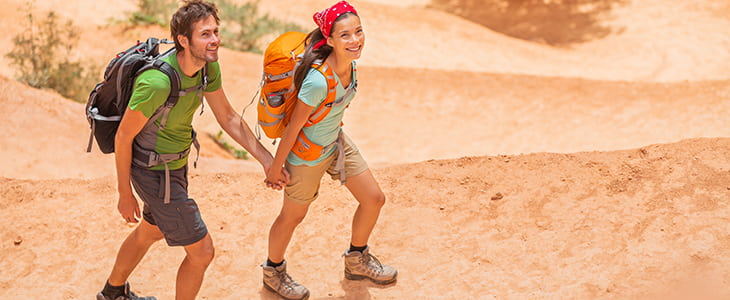 Two hikers smile and walk in desert canyon