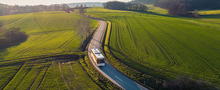 A single charter bus drives on a rural highway