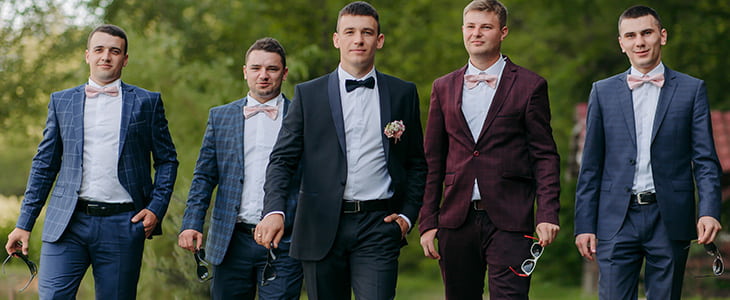 Groomsmen and a groom pose laugh 