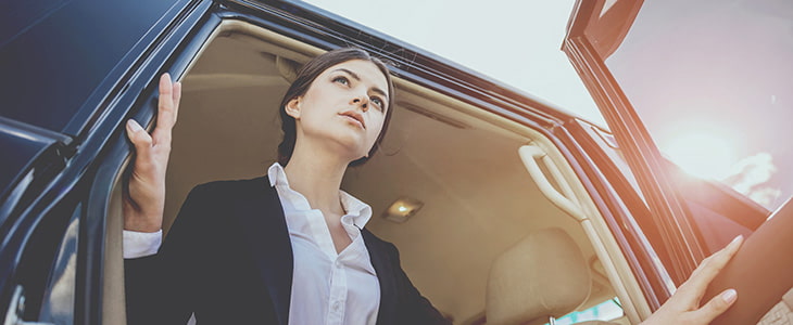 A businesswoman in a suit sitting in a black shuttle bus.