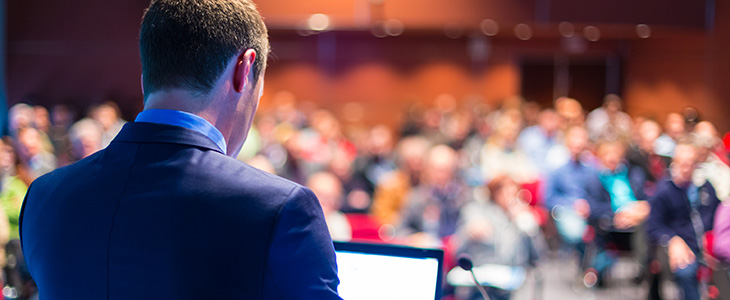 A keynote speaker at a conference addressing an audience.