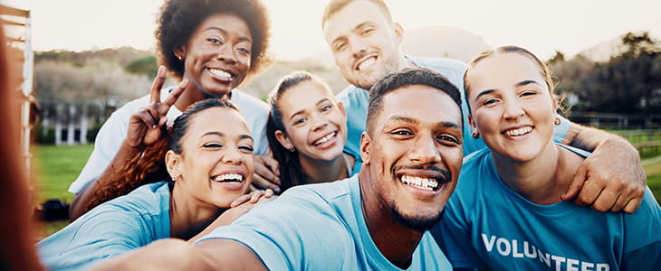 A group of volunteers pose for a selfie in a park