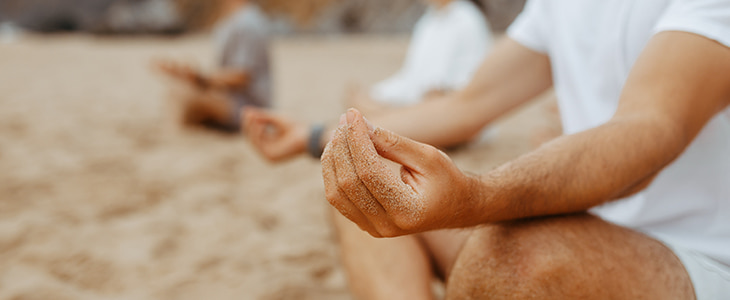 A group of people meditate on a beach