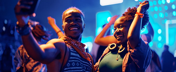 Concert attendees take a selfie in front of a dim stage