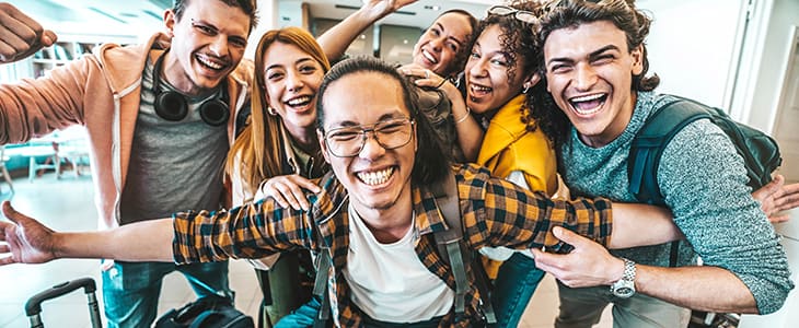 A group of travelers with suitcases smile in an airport