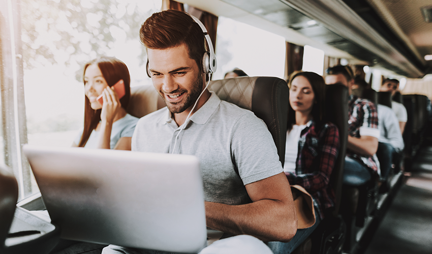 a man sits in a charter bus seat and smiles