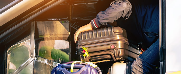 A driver loading a charter bus with baggage.